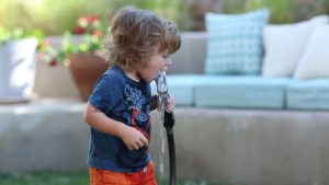 toddler drinking water from hose